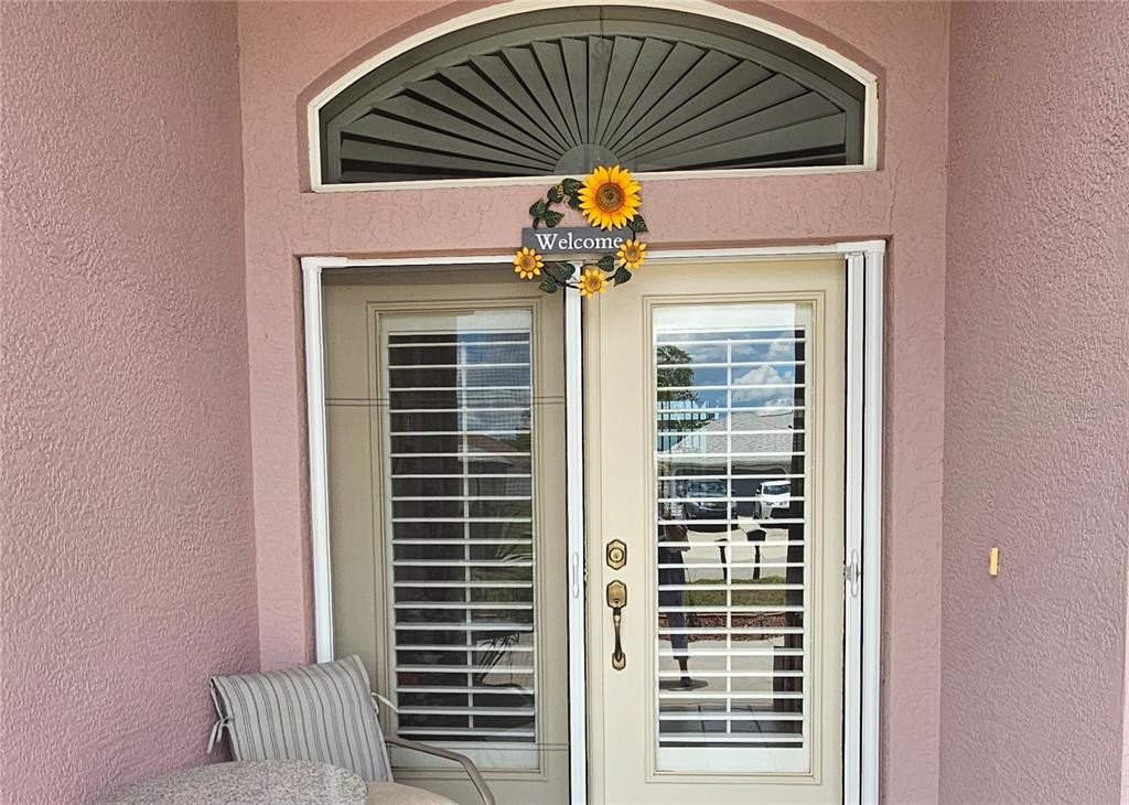 A pink exterior wall features a double glass door with blinds and a sunflower wreath — 8357 DENARGO ROAD, NORTH PORT, FL