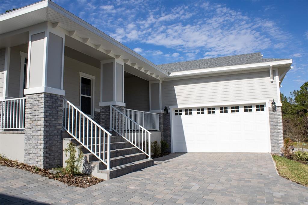 A house exterior features a gray brick base, white siding, a covered porch, and a garage — 3970 SOUTHERN VALLEY LOOP, BROOKSVILLE, FL