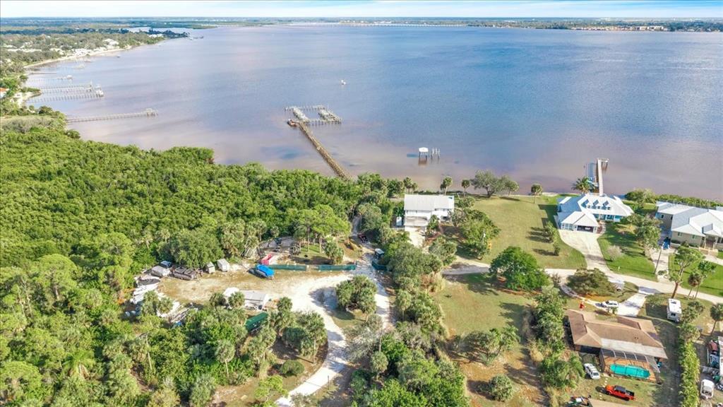 An aerial view shows a waterfront property with a long pier, trees, and several houses — 23465 HARBORVIEW ROAD UNIT 723, PORT CHARLOTTE, FL