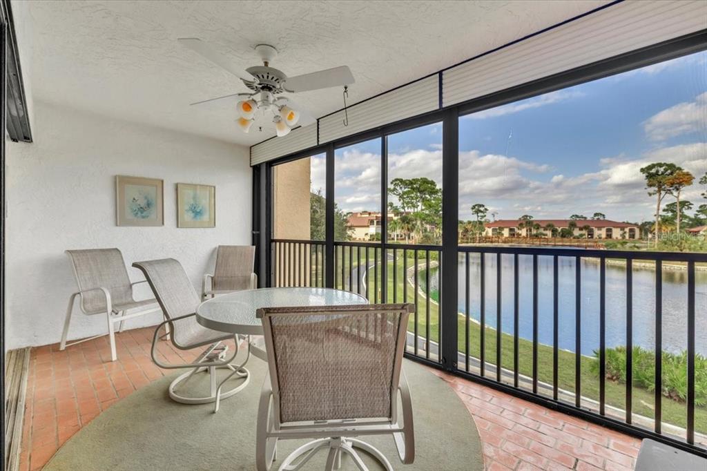 A screened-in balcony with patio furniture overlooks a lake and residential buildings — 23465 HARBORVIEW ROAD UNIT 723, PORT CHARLOTTE, FL