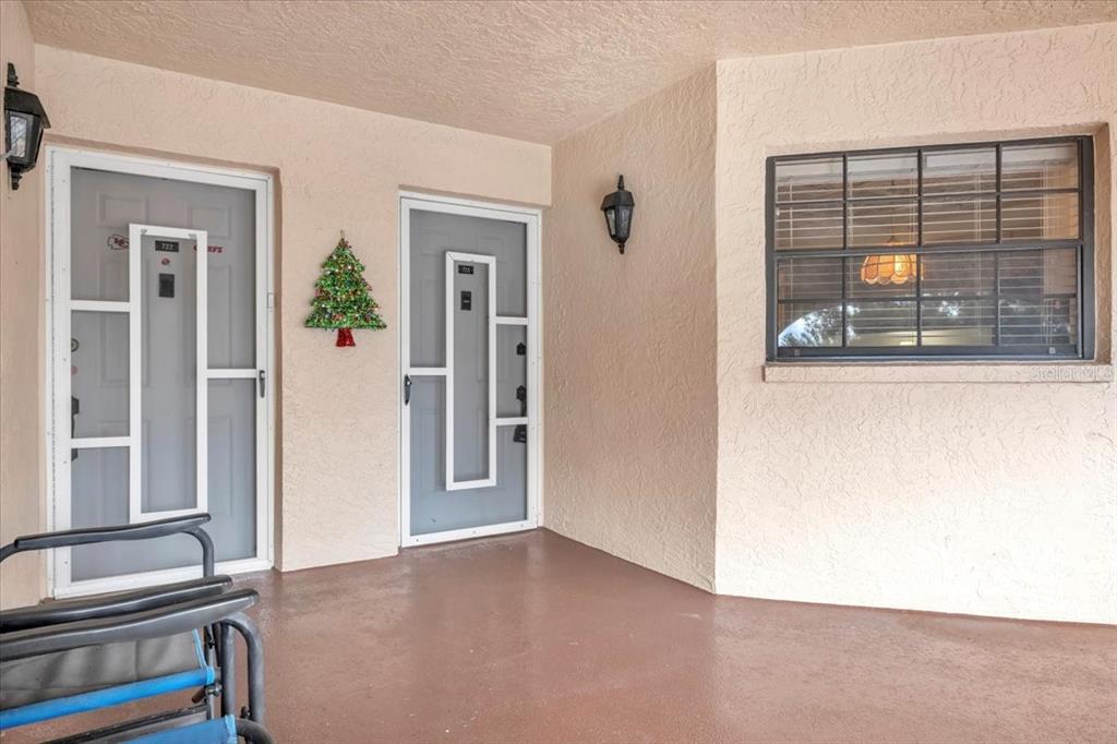 A covered porch features two grey screen doors, a Christmas tree decoration, and a window — 23465 HARBORVIEW ROAD UNIT 723, PORT CHARLOTTE, FL