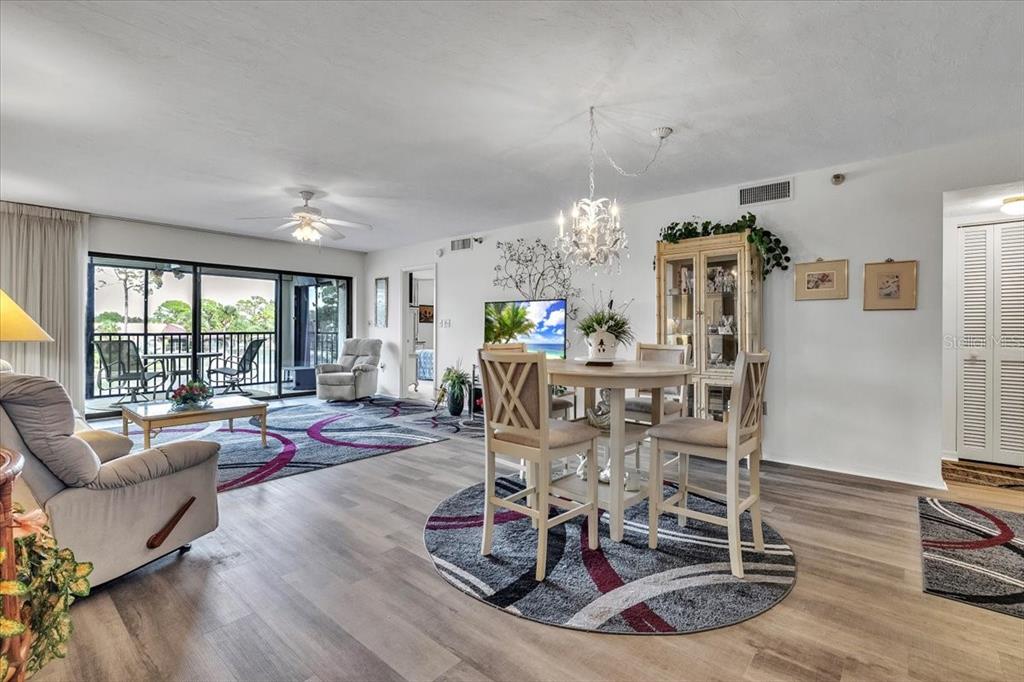 A living and dining area features wood-look flooring, a ceiling fan, and a balcony view — 23465 HARBORVIEW ROAD UNIT 723, PORT CHARLOTTE, FL