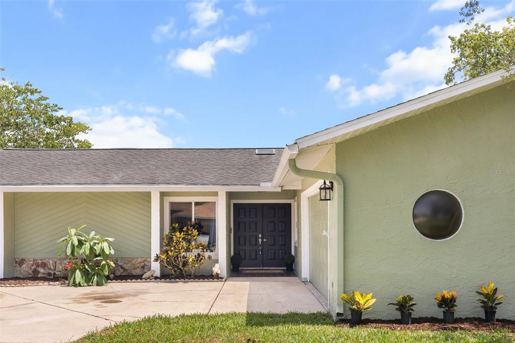 A light green house exterior features a dark double front door and a circular window — 12512 WILLOW TREE AVENUE, HUDSON, FL
