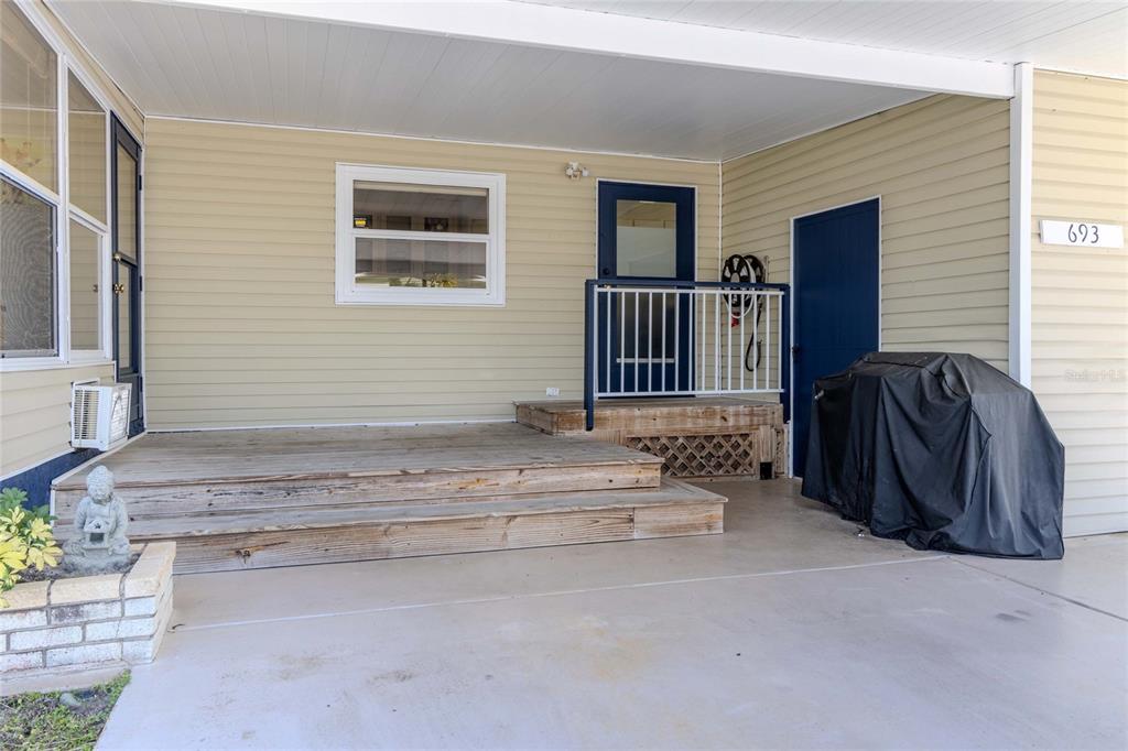 A covered porch with wooden steps leads to a blue door and a storage closet — 2100 KINGS HIGHWAY CRESCENT UNIT 693, PORT CHARLOTTE, FL