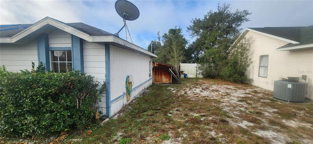 The exterior of a house with white siding, a satellite dish, and a side yard — 2788 W COVINGTON DRIVE, DELTONA, FL