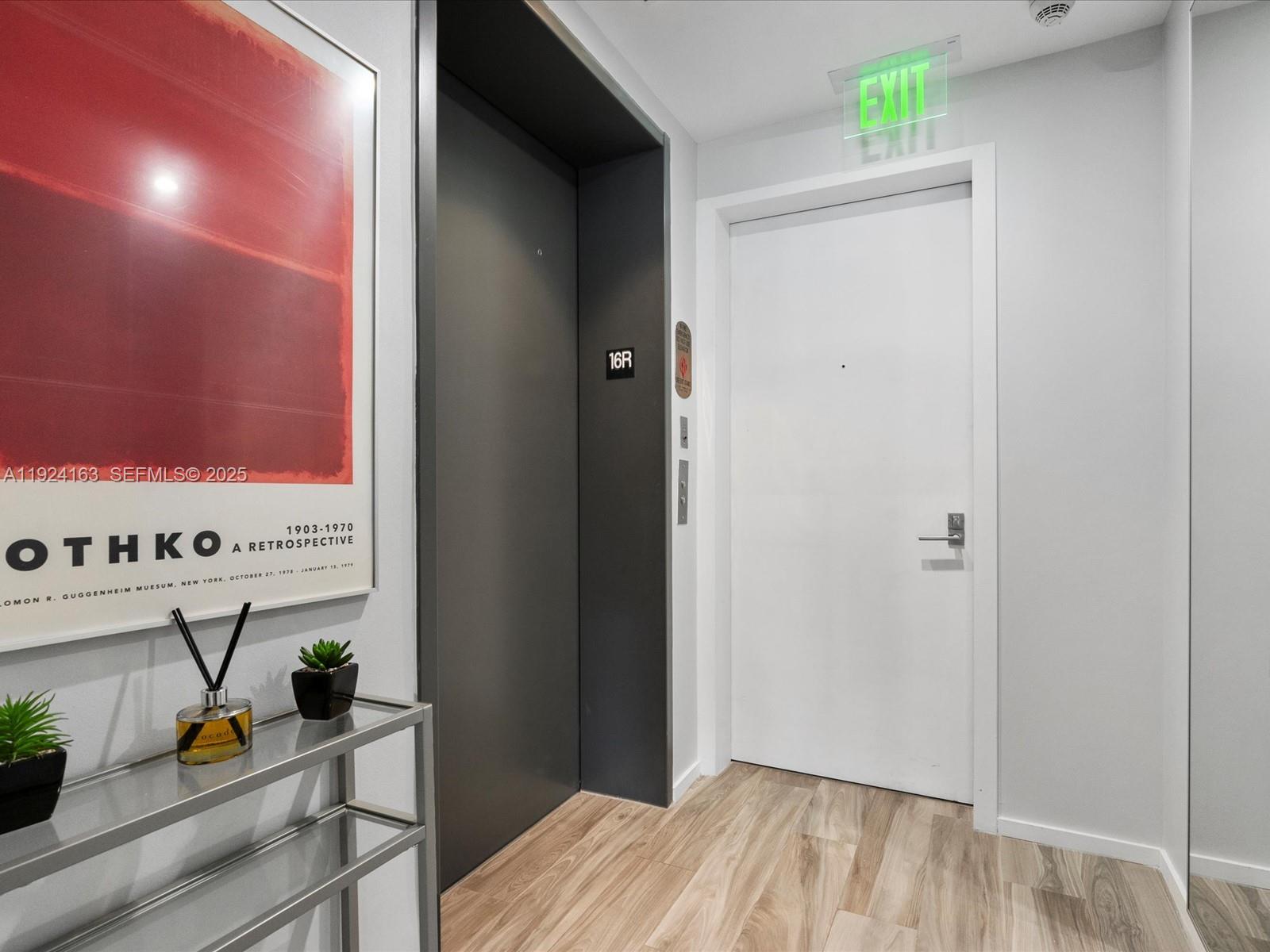 A hallway features a white door, a dark elevator door labeled 16R, and framed artwork — 801 S Miami Ave # 1603, Miami FL 33130, MIAMI, FL