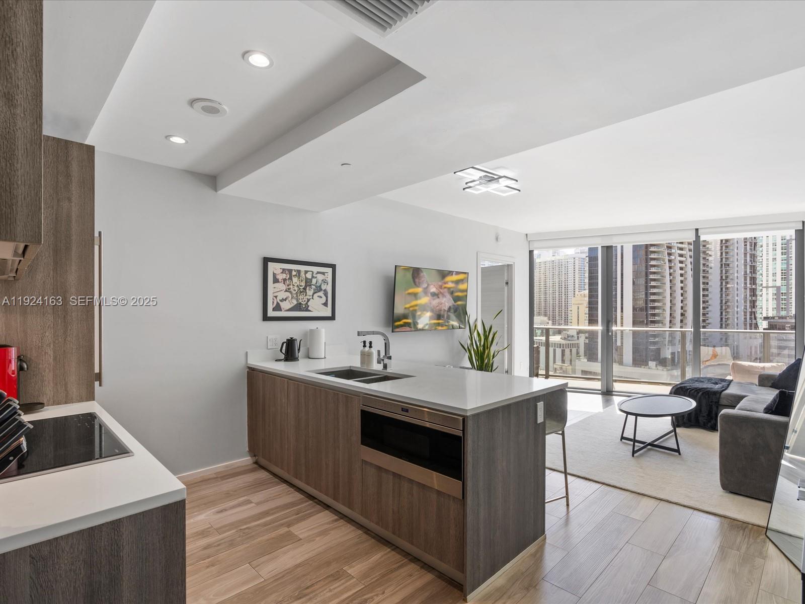A modern kitchen island with a built-in microwave faces a living area with city views — 801 S Miami Ave # 1603, Miami FL 33130, MIAMI, FL