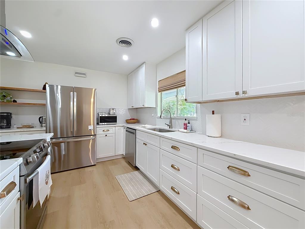 A modern kitchen features white cabinets, stainless steel appliances, and light wood flooring — 848 SE 23RD STREET, OCALA, FL