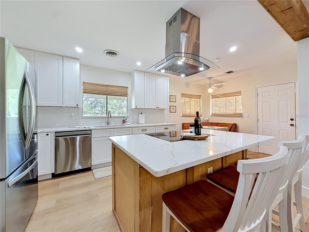 A kitchen features white cabinets, a marble-topped island with a cooktop, and stainless steel appliances — 848 SE 23RD STREET, OCALA, FL