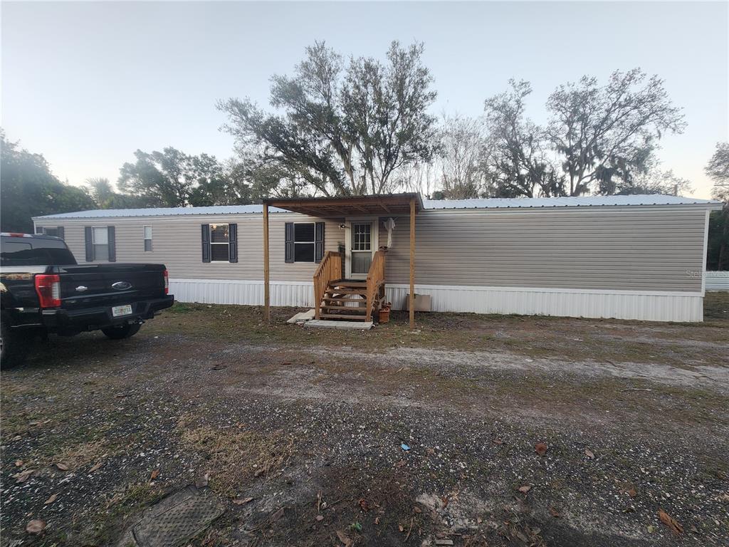 A single-story manufactured home with light siding, a metal roof, and a wooden porch — 1333 WILKINSON DRIVE, PLANT CITY, FL