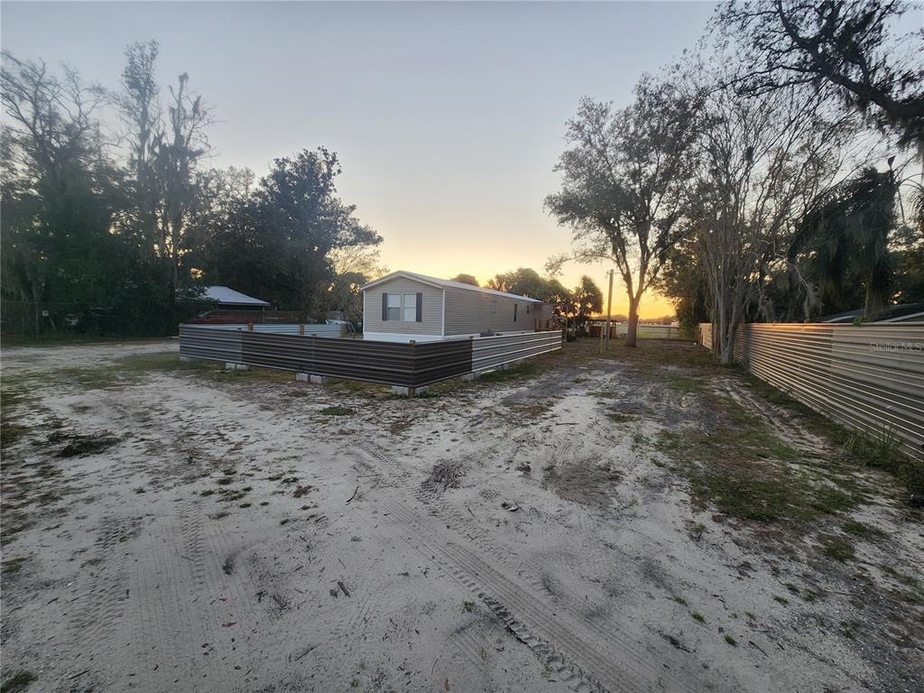 A manufactured home sits on a sandy lot enclosed by a corrugated metal fence — 1333 WILKINSON DRIVE, PLANT CITY, FL