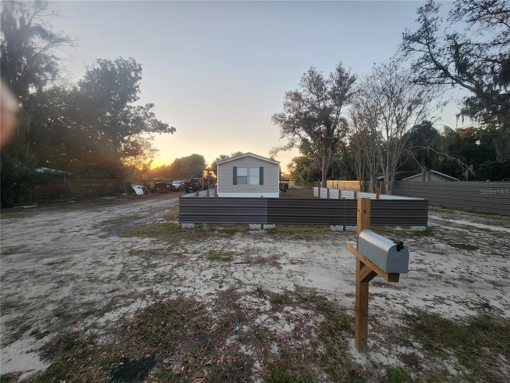 A manufactured home sits on a sandy lot behind a corrugated metal fence — 1333 WILKINSON DRIVE, PLANT CITY, FL