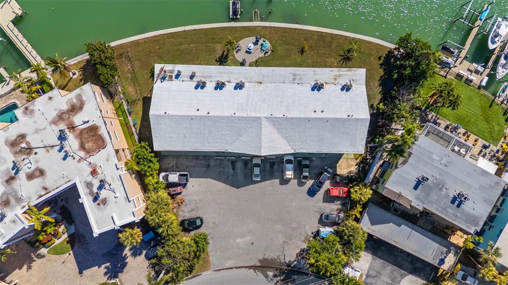 An aerial view shows a multi-unit building with a parking lot and waterfront access — 275 116TH AVENUE, TREASURE ISLAND, FL