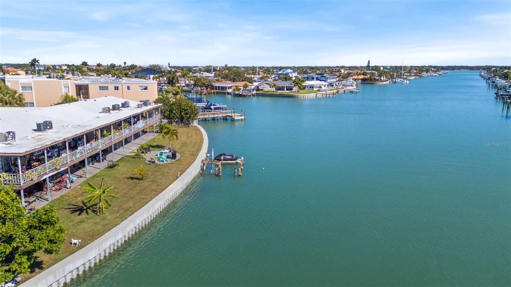 An aerial view shows a waterfront apartment building with a lawn and boat docks — 275 116TH AVENUE, TREASURE ISLAND, FL