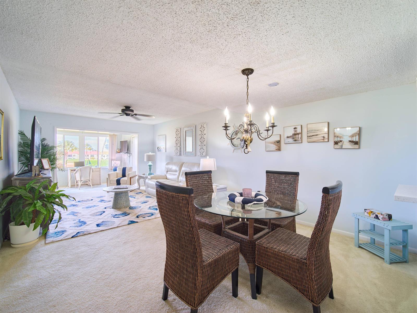 A dining area with a glass table and wicker chairs opens into a living room — 5363 SE Miles Grant Road # D202, Stuart FL 34997, STUART, FL