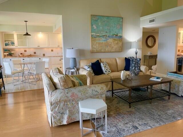 A living room with a beige sofa, patterned armchair, and an open kitchen in the background — 1000 N Us Highway 1, Jupiter FL 33477, JUPITER, FL