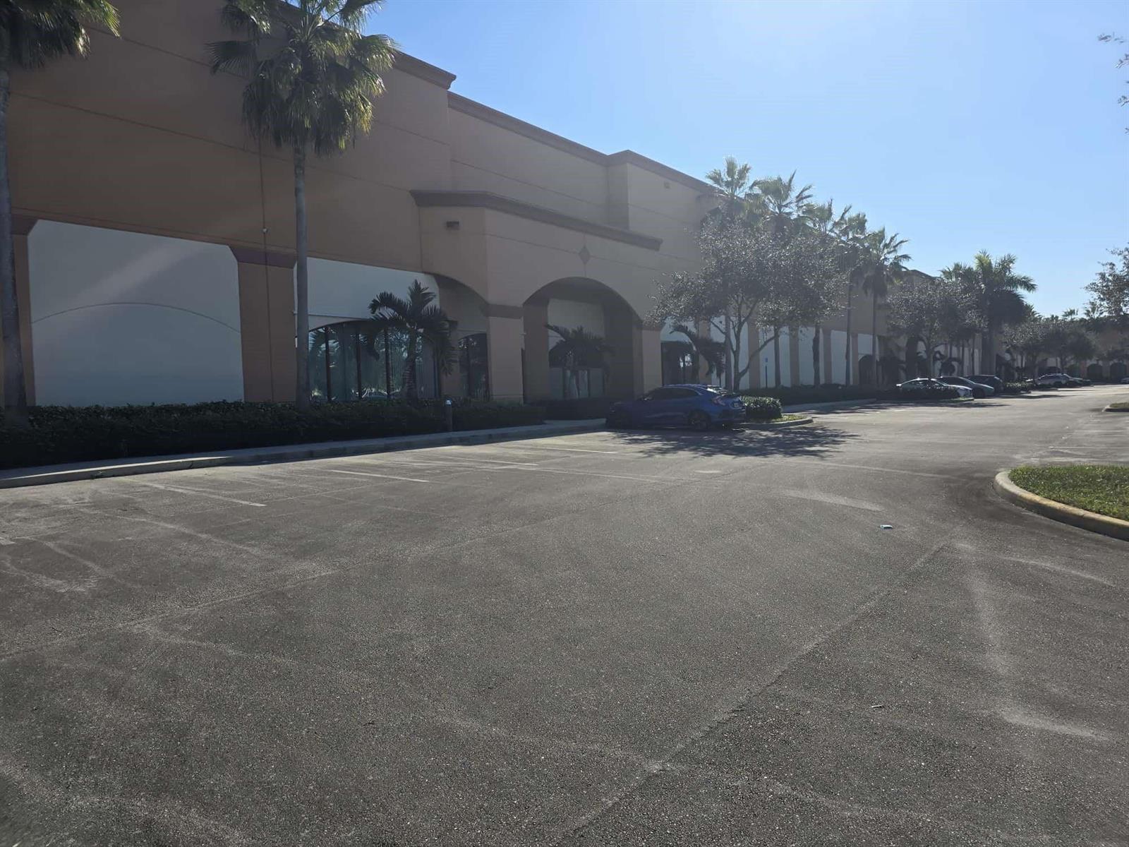 A large commercial building exterior features a tan facade, arched entrance, and palm trees — 9608-9616 Premier Parkway, Miramar FL 33025, MIRAMAR, FL
