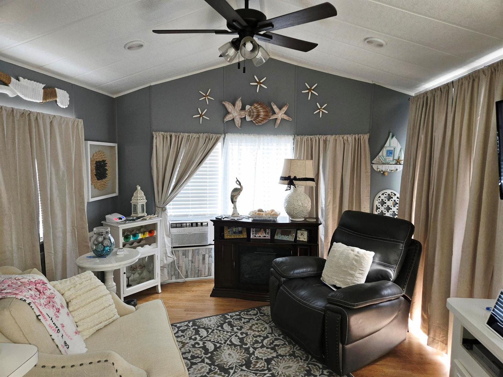 A living room features a dark leather recliner, a sofa, and coastal-themed wall decor — 14270 SE 124th, Okeechobee FL 34974, OKEECHOBEE, FL