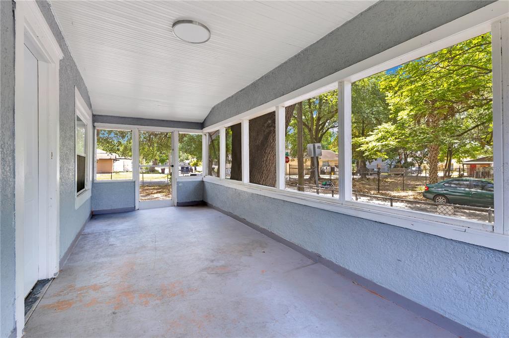 A screened-in porch with a concrete floor, white ceiling, and large windows overlooking a yard — 1029 COLYER STREET, ORLANDO, FL