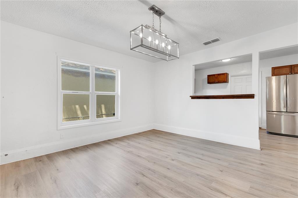 A dining area features light wood-look flooring, white walls, and a rectangular metal chandelier — 1029 COLYER STREET, ORLANDO, FL
