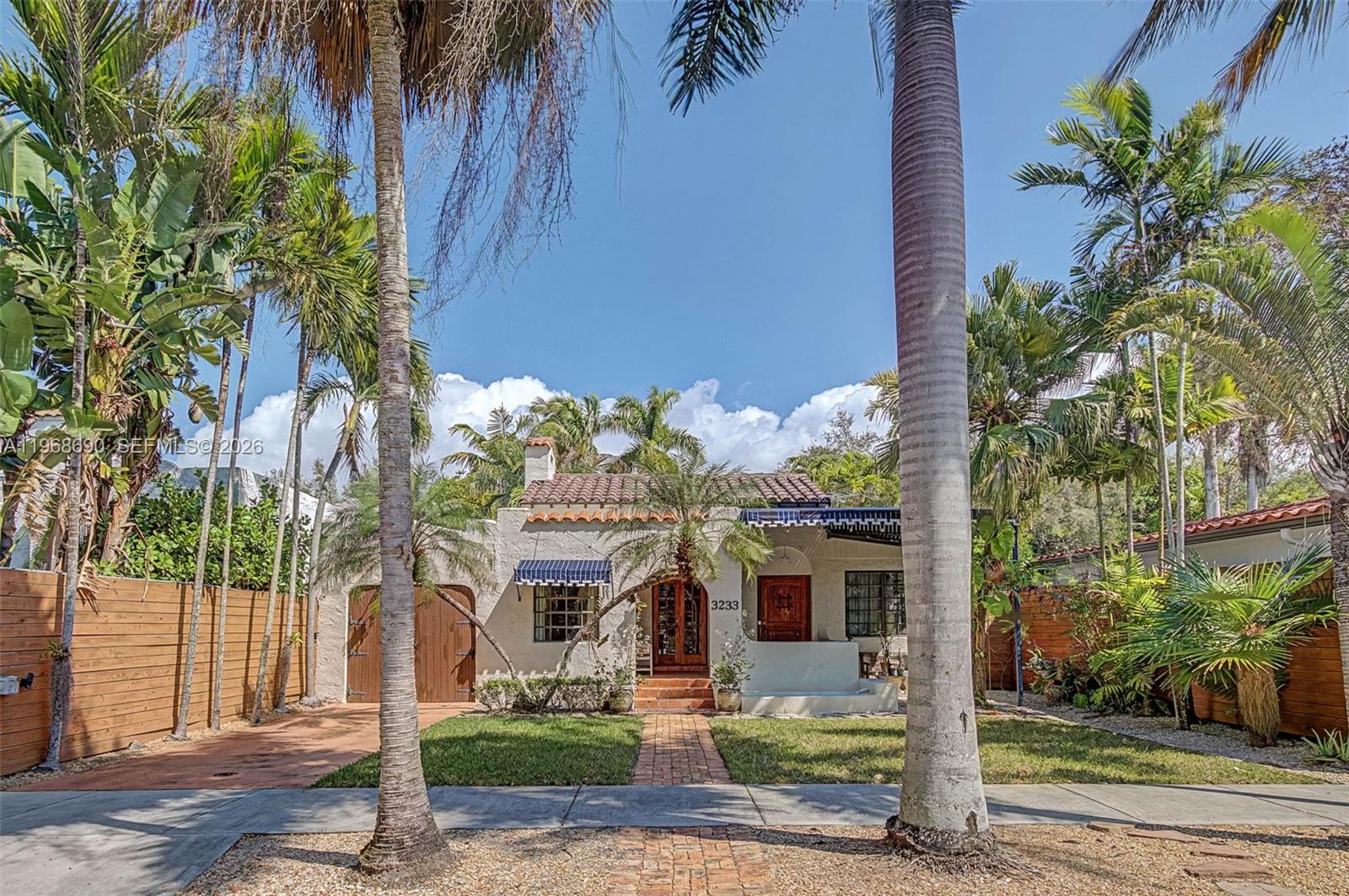 A single-story stucco house with a tiled roof, arched entryway, and palm trees in front — 3233 Crystal Ct, Miami FL 33133, MIAMI, FL