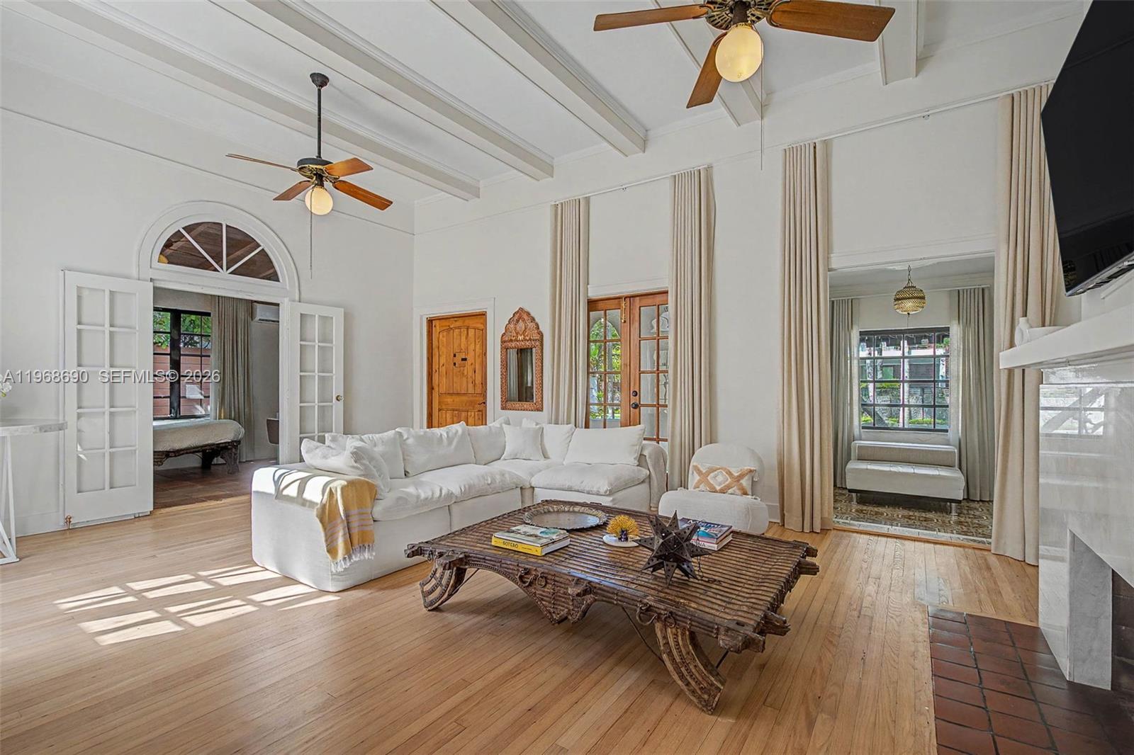 A bright living room features a white sectional sofa, a carved wooden coffee table, and ceiling fans — 3233 Crystal Ct, Miami FL 33133, MIAMI, FL