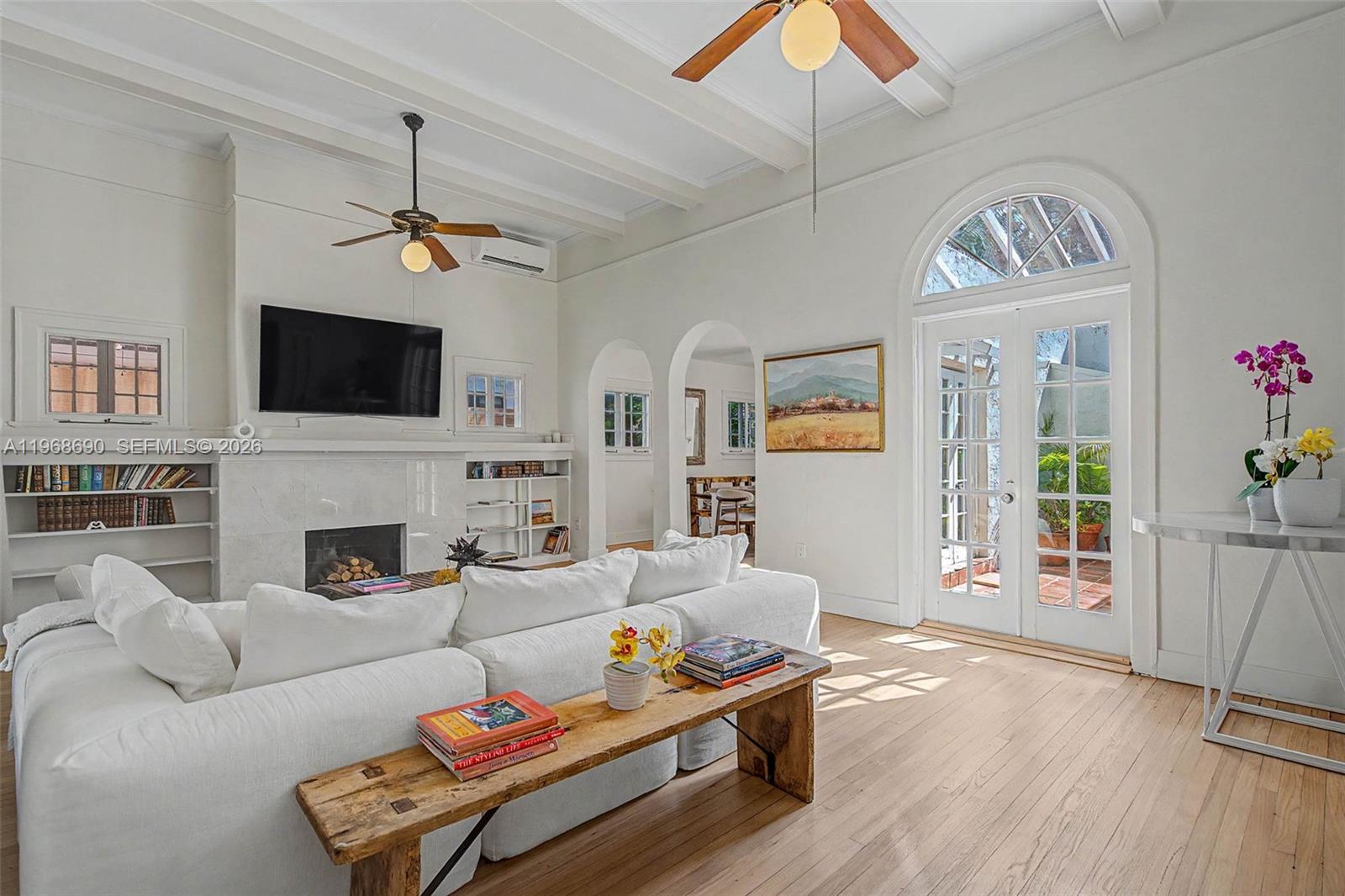 A bright living room features a white sofa, a fireplace, arched doorways, and glass doors — 3233 Crystal Ct, Miami FL 33133, MIAMI, FL