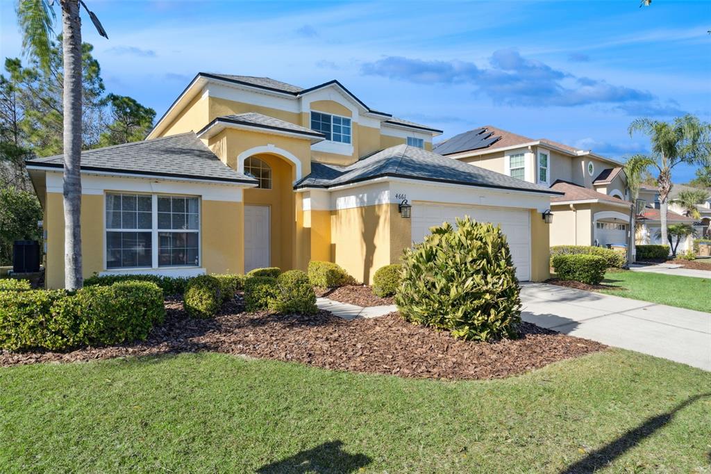 A two-story yellow stucco house features a front-facing garage and a landscaped front yard — 4661 GOLDEN BEACH COURT, KISSIMMEE, FL