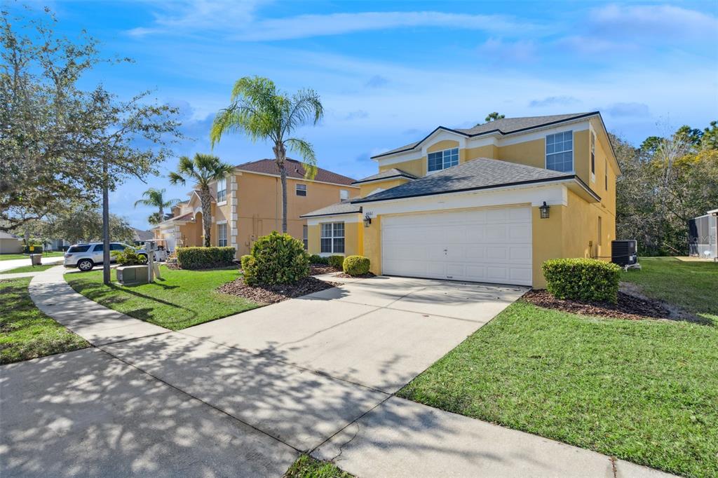 A two-story yellow house with a white garage door and a concrete driveway — 4661 GOLDEN BEACH COURT, KISSIMMEE, FL
