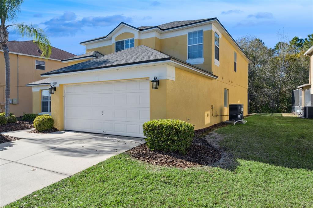 A two-story yellow house with a white garage door and a landscaped front yard — 4661 GOLDEN BEACH COURT, KISSIMMEE, FL