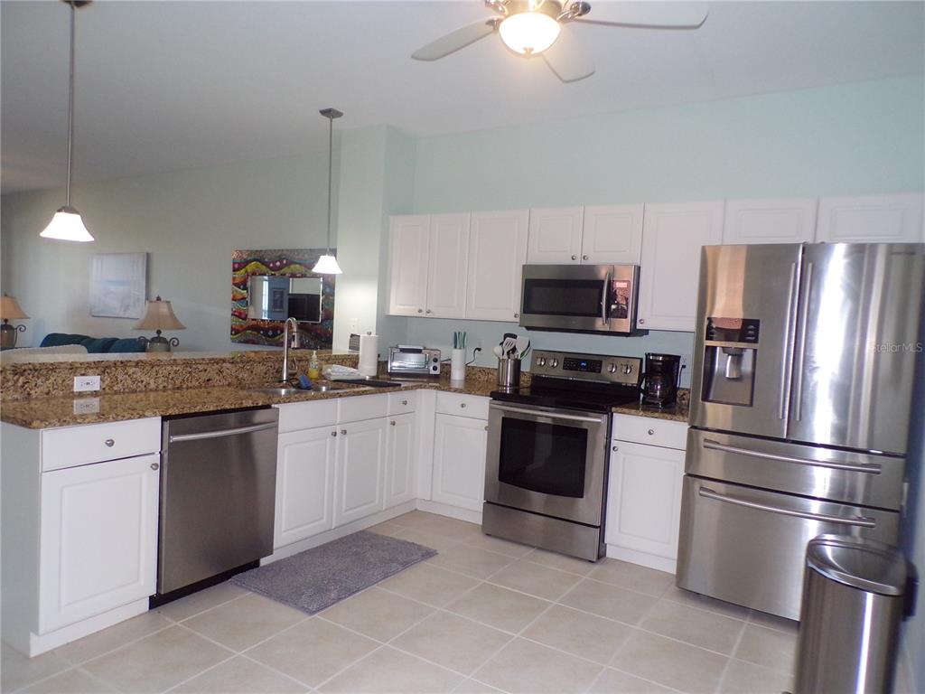A kitchen features white cabinets, granite countertops, stainless steel appliances, and tile flooring — 3500 MONDOVI COURT UNIT 811, PUNTA GORDA, FL
