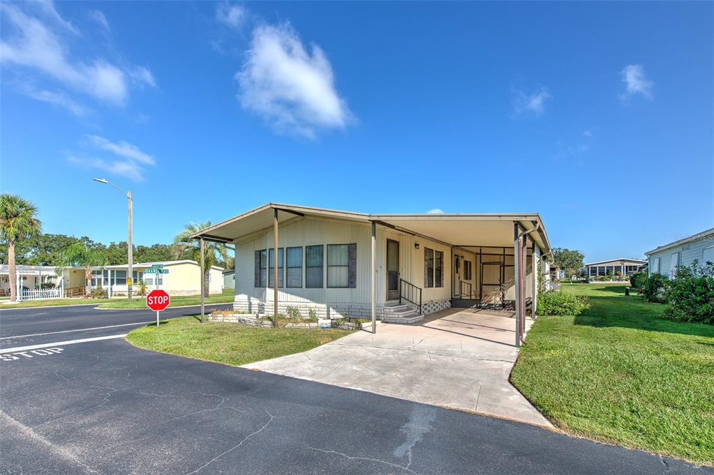 A single-story manufactured home with a carport and a stop sign in the front yard — 37605 AMIGO DRIVE, ZEPHYRHILLS, FL