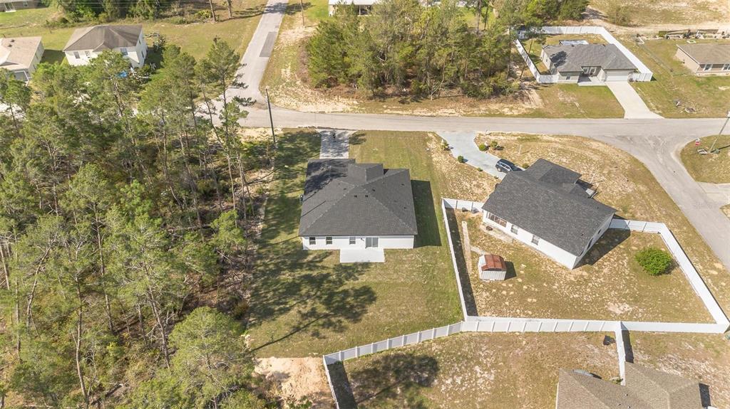 An aerial view shows two houses with dark roofs and white fences in a suburban neighborhood — 4411 SW 172ND STREET ROAD, OCALA, FL