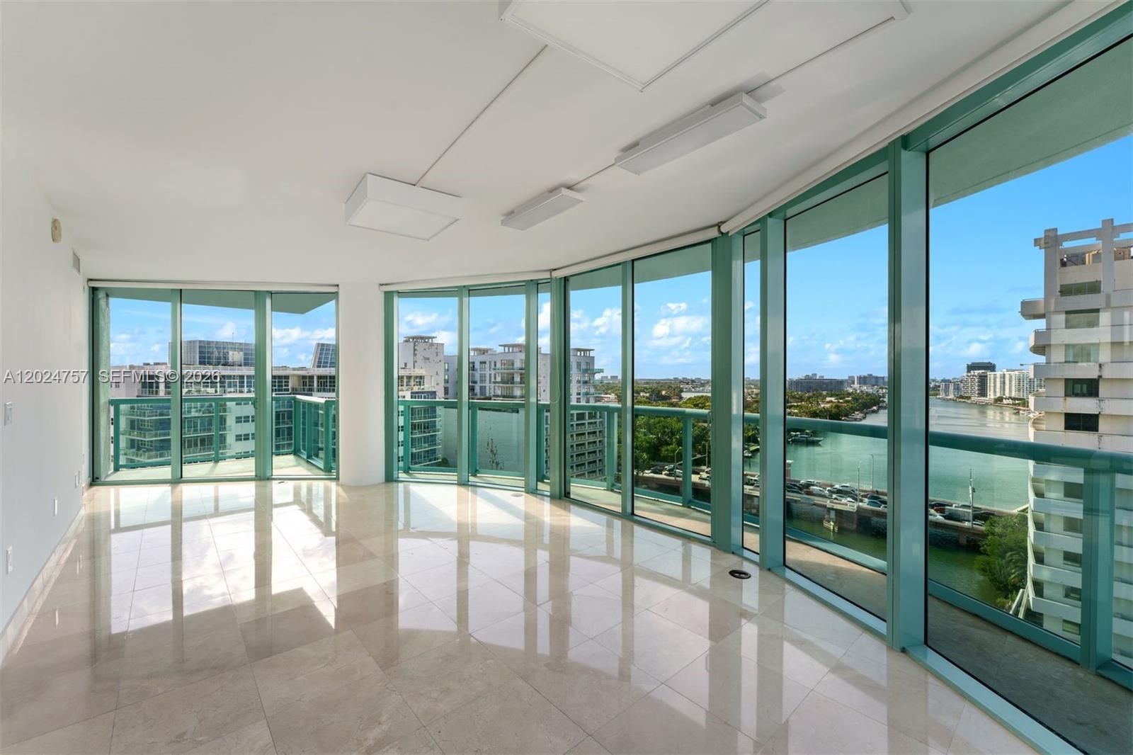 An empty room with light tile floors and floor-to-ceiling windows overlooking a waterway — 6000 Indian Creek Dr # 14B, Miami Beach FL 33140, MIAMI BEACH, FL