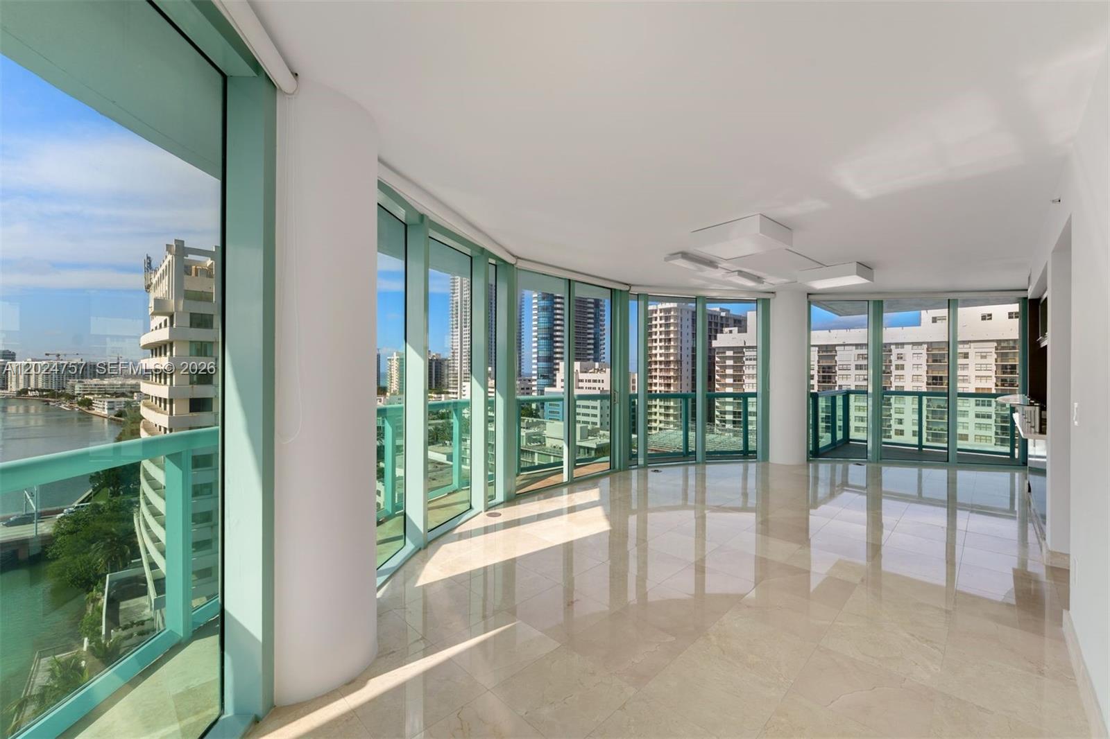 An empty room with polished tile floors, floor-to-ceiling windows, and views of city buildings — 6000 Indian Creek Dr # 14B, Miami Beach FL 33140, MIAMI BEACH, FL
