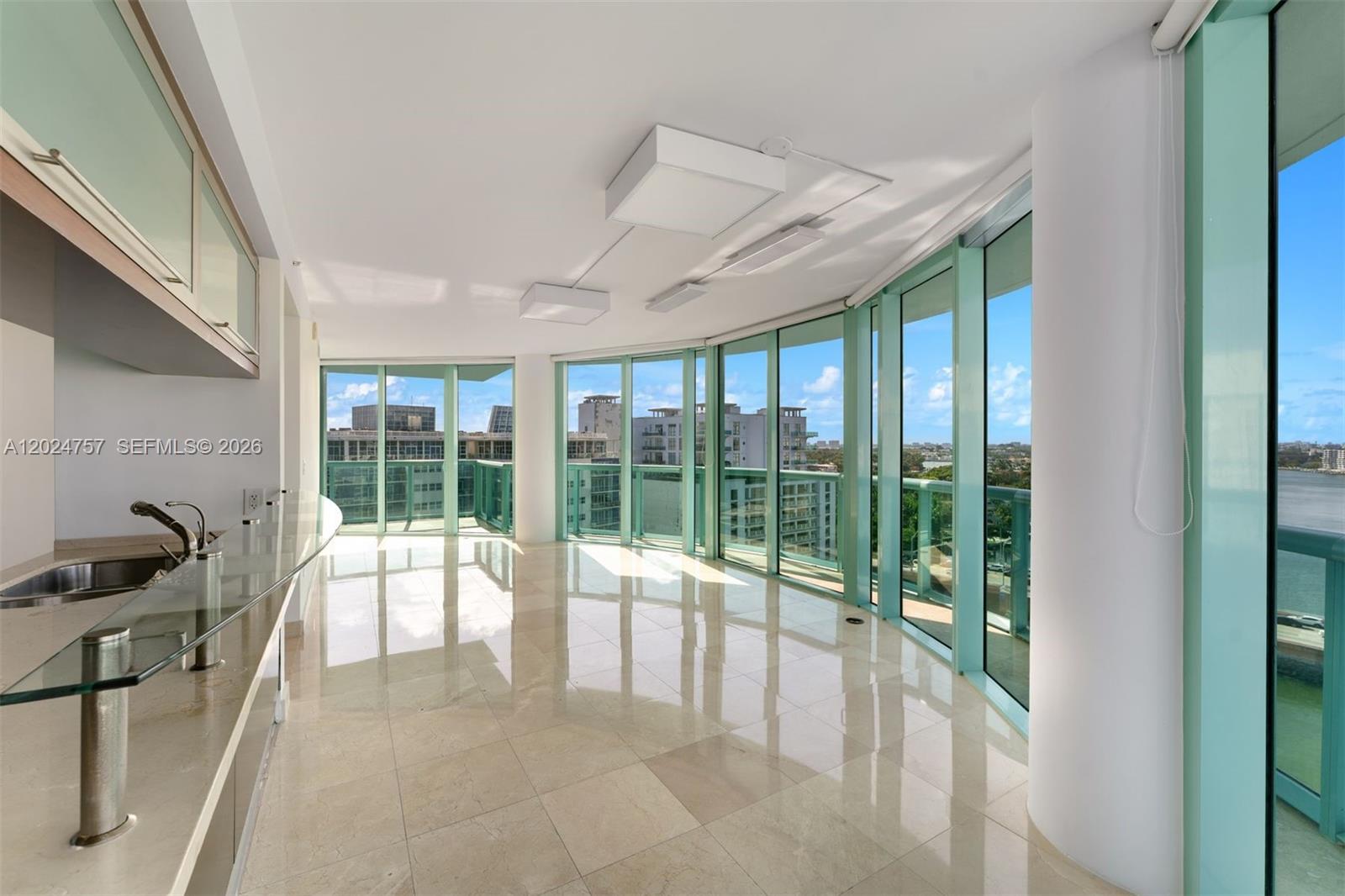 A modern kitchen and living area with floor-to-ceiling windows and light-colored tile flooring — 6000 Indian Creek Dr # 14B, Miami Beach FL 33140, MIAMI BEACH, FL