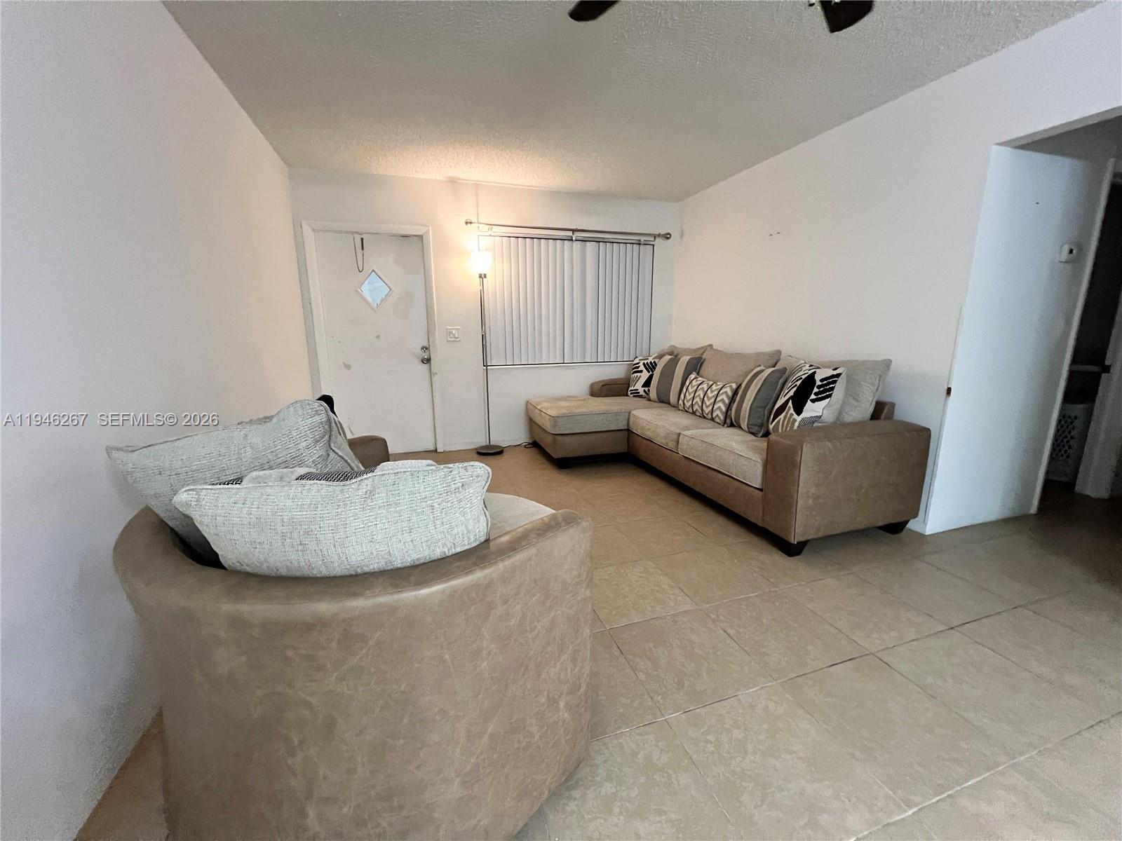A living room features a tan sectional sofa, a matching armchair, and light tile flooring — 2702 Pierce St # 5, Hollywood FL 33020, HOLLYWOOD, FL