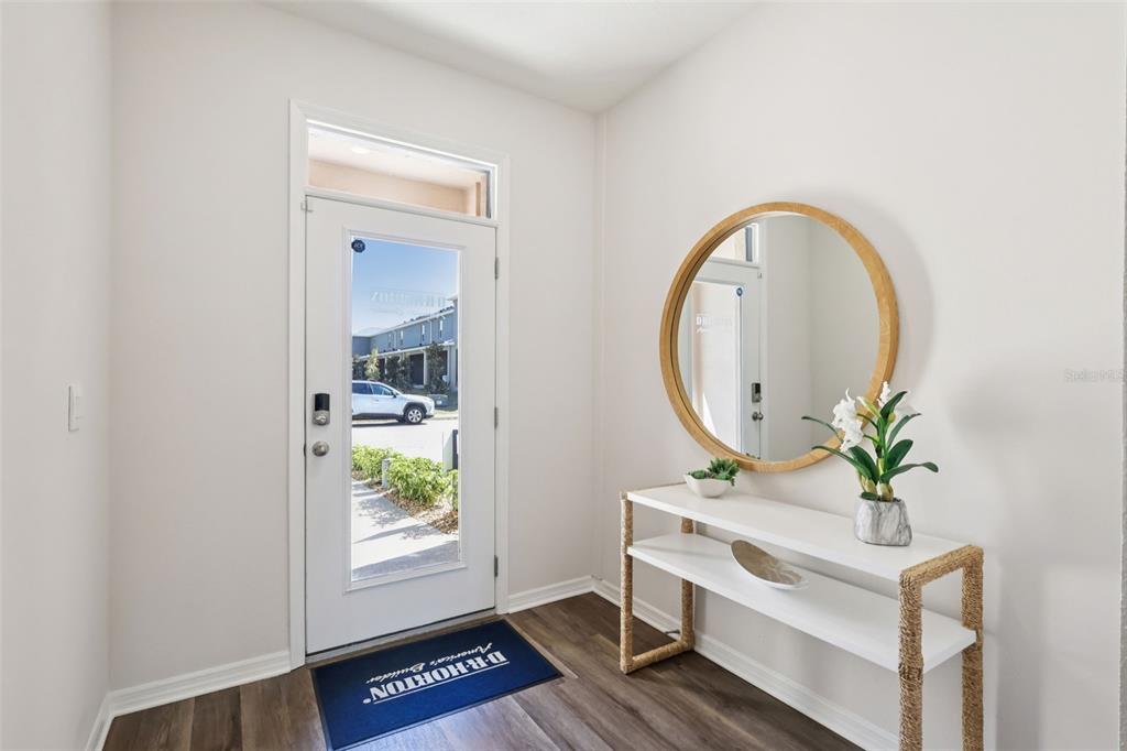 An entryway features a white front door, a round mirror, and a white console table — 2554 OLYMPIC COURT, DAVENPORT, FL