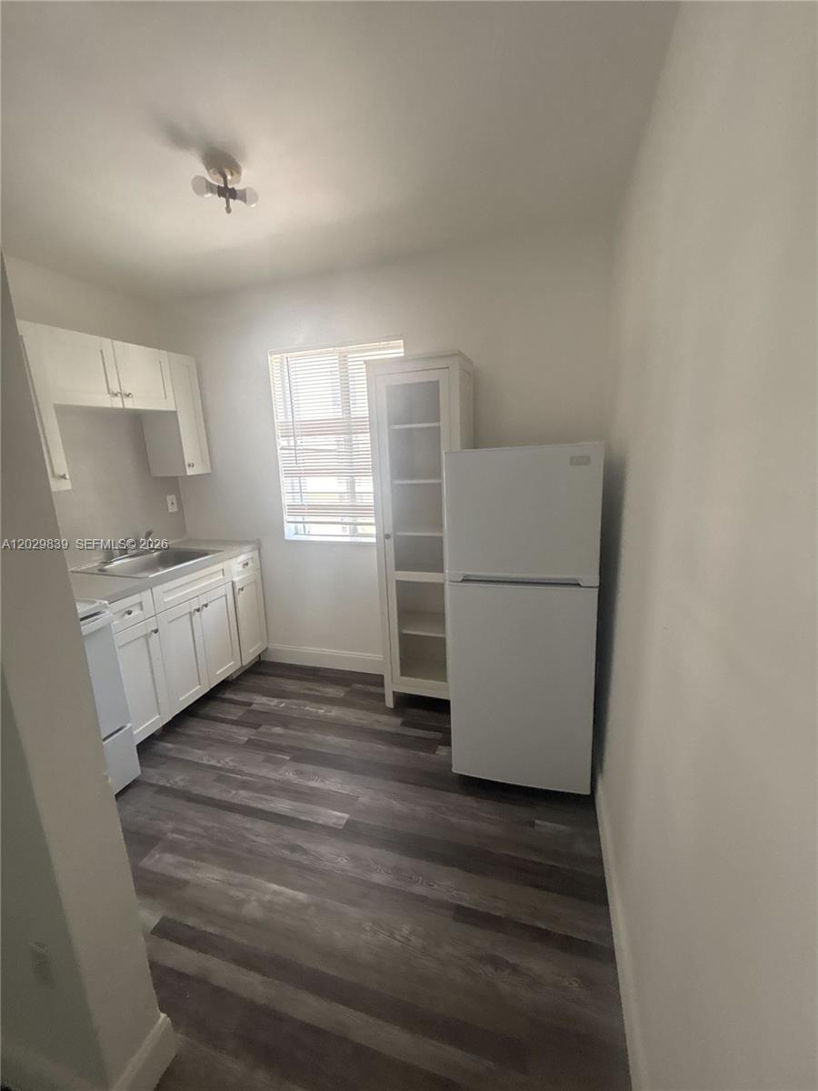 This kitchen features white cabinets, a stainless steel sink, a refrigerator, and wood-look flooring — 542 NW 8th St # 11, Miami FL 33136, MIAMI, FL