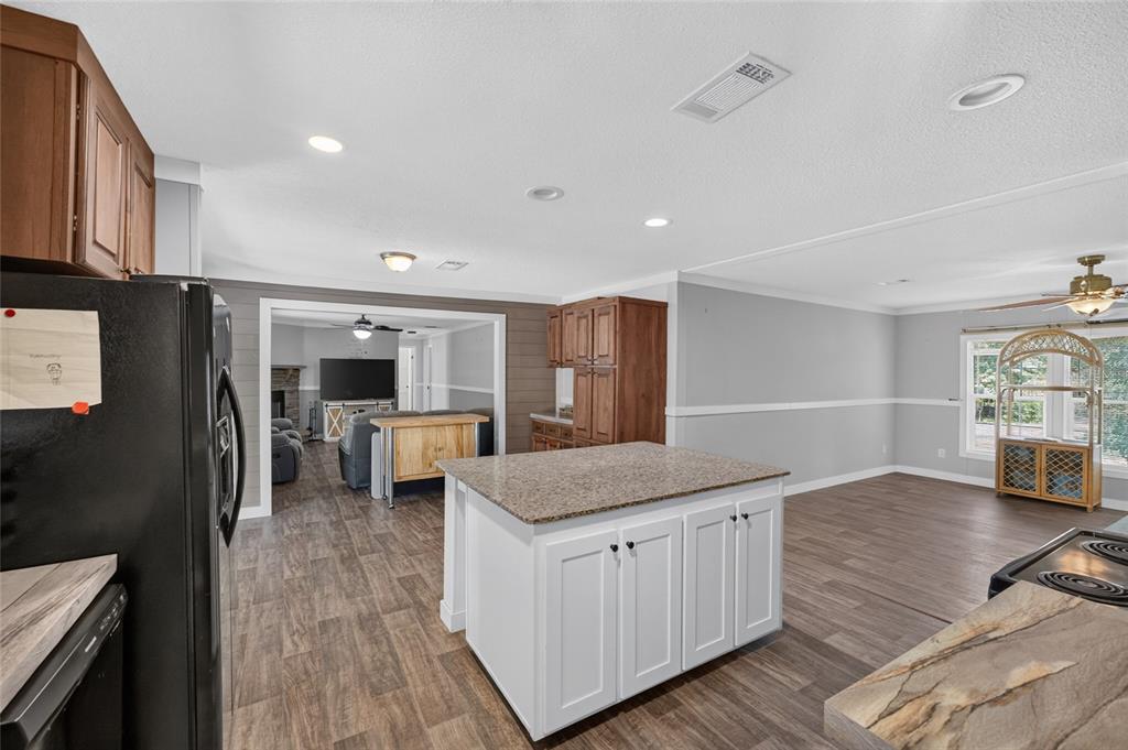 A kitchen with a white island and granite countertops overlooks a living room area — 4830 NE 121 AVENUE, WILLISTON, FL