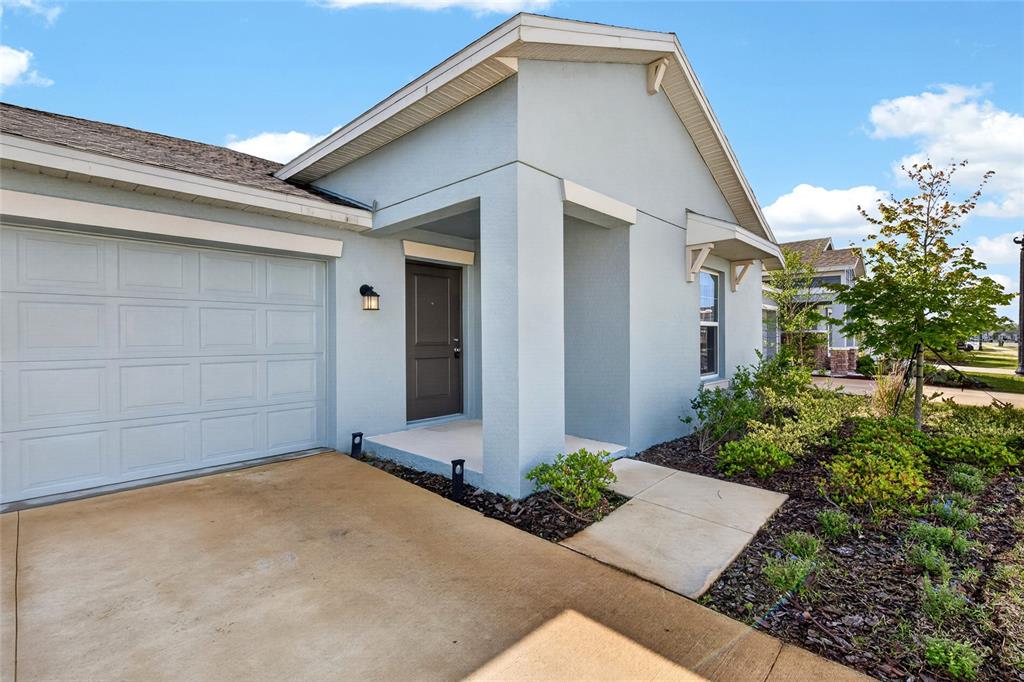 The exterior of a light blue house features a garage, front porch, and landscaped yard — 2212 GREEN VALLEY STREET, DAYTONA BEACH, FL