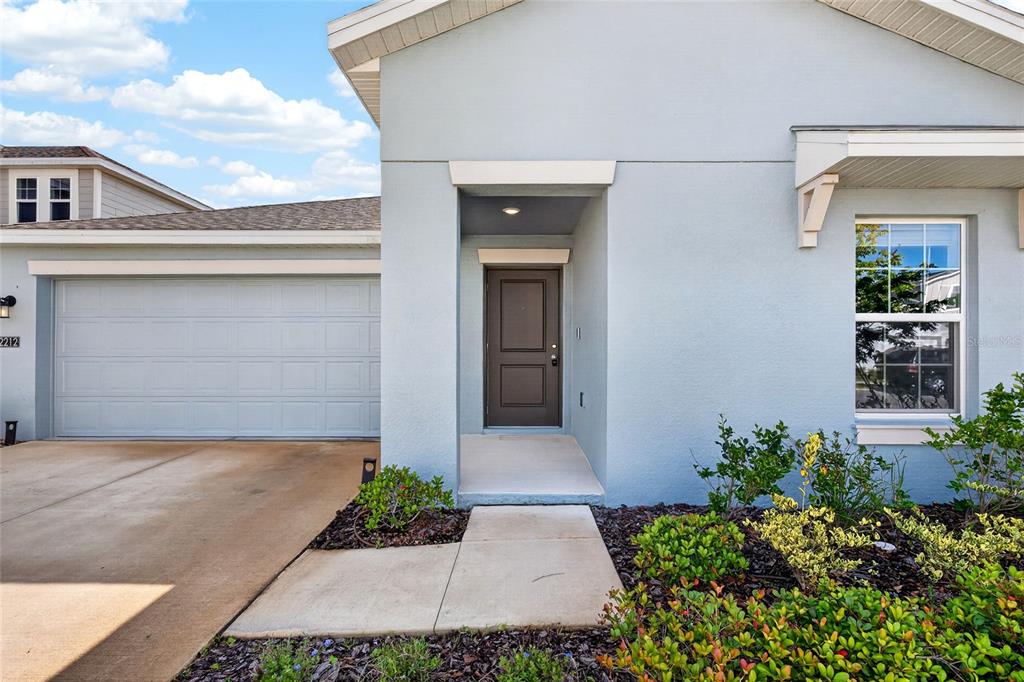 The exterior of a light blue house features a garage, a front door, and landscaping — 2212 GREEN VALLEY STREET, DAYTONA BEACH, FL