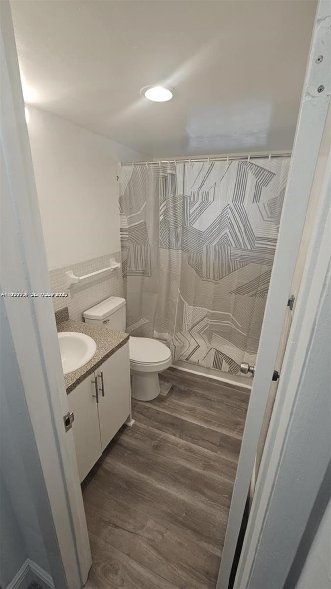A small bathroom features a white vanity, a toilet, and a patterned shower curtain — 1500 NE 127th St # 103, North Miami FL 33161, NORTH MIAMI, FL