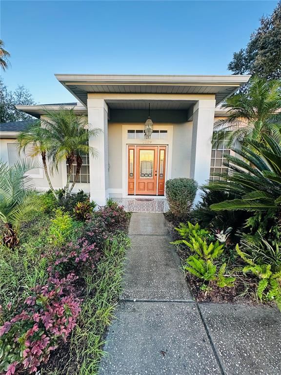 A concrete walkway leads to the front entrance of a house with a covered porch — 1889 RANCHLAND TRAIL, LONGWOOD, FL
