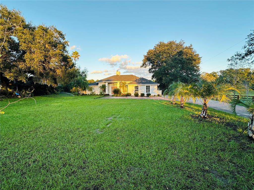 A single-story house with a paved driveway sits on a large, grassy lawn with trees — 1889 RANCHLAND TRAIL, LONGWOOD, FL