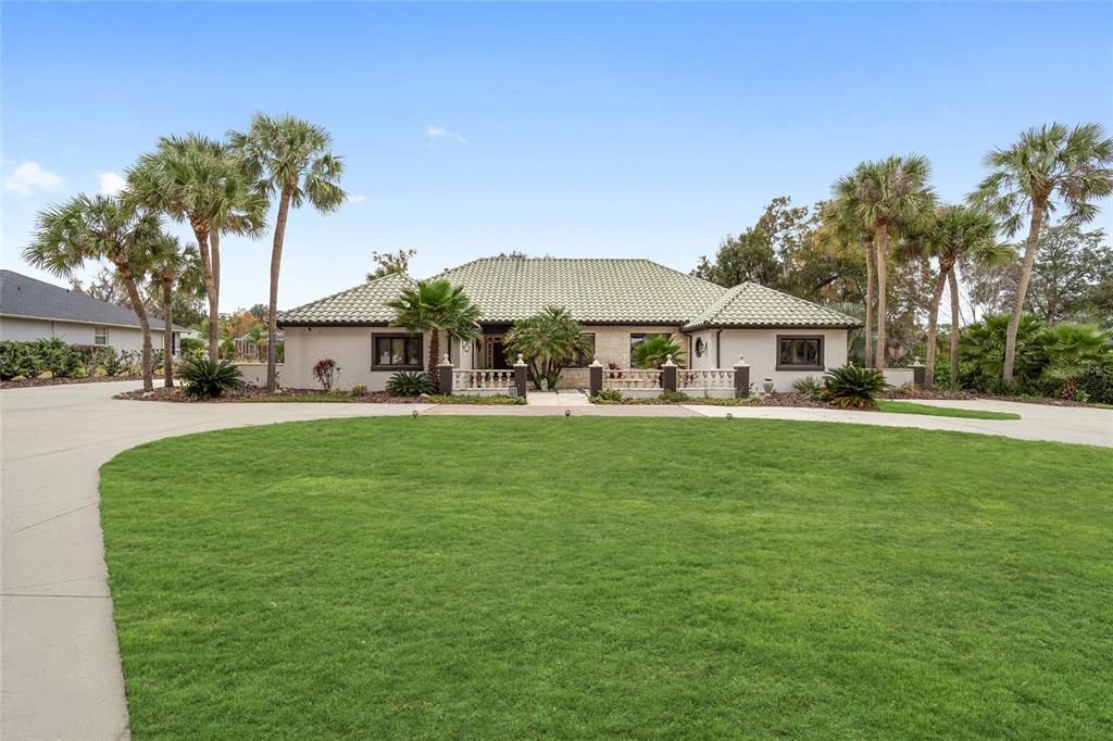 A single-story house with a light-colored exterior, a green tile roof, and a circular driveway — 2023 SE LAUREL RUN DRIVE, OCALA, FL