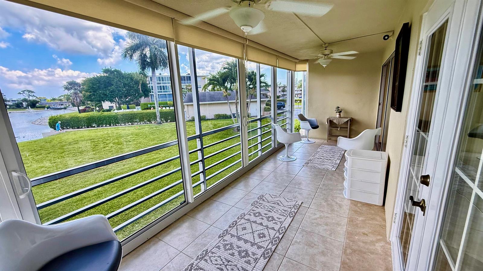 A tiled sunroom features floor-to-ceiling windows overlooking a grassy lawn and a water view — 2728 N Garden Dr Drive N # 214, FL 33461, FL