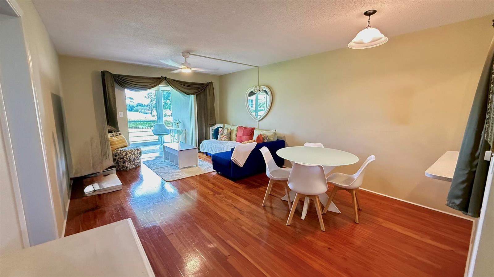 A living and dining area with hardwood floors, a blue sofa, and a glass table — 2728 N Garden Dr Drive N # 214, FL 33461, FL