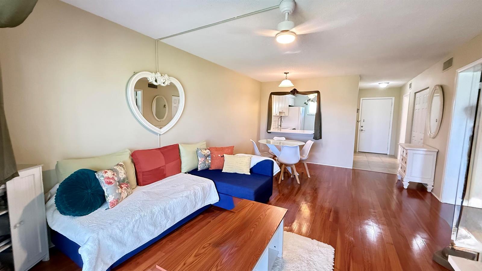A living room features a blue sectional sofa, wood flooring, and a dining area — 2728 N Garden Dr Drive N # 214, FL 33461, FL