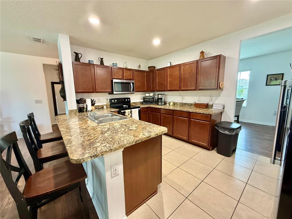 A kitchen features dark wood cabinets, granite countertops, a center island, and tile flooring — 331 ALDER AVENUE SE, PALM BAY, FL